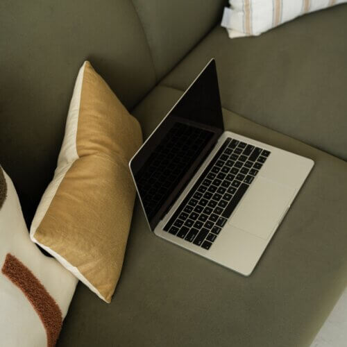 laptop on green couch with yellow pillow