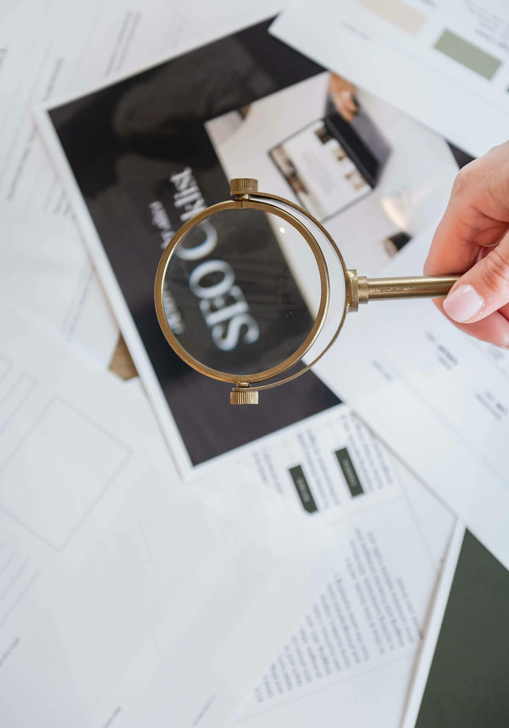 Image of Southern Creative owner, Stephanie O'Keefe, holding a magnifying glass over SEO strategy papers helping strategize how to get found online with seo.