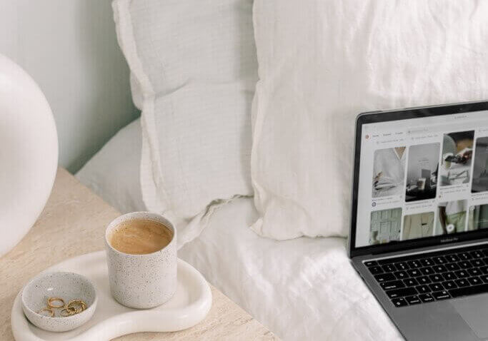 computer with products on wordpress website next to bed